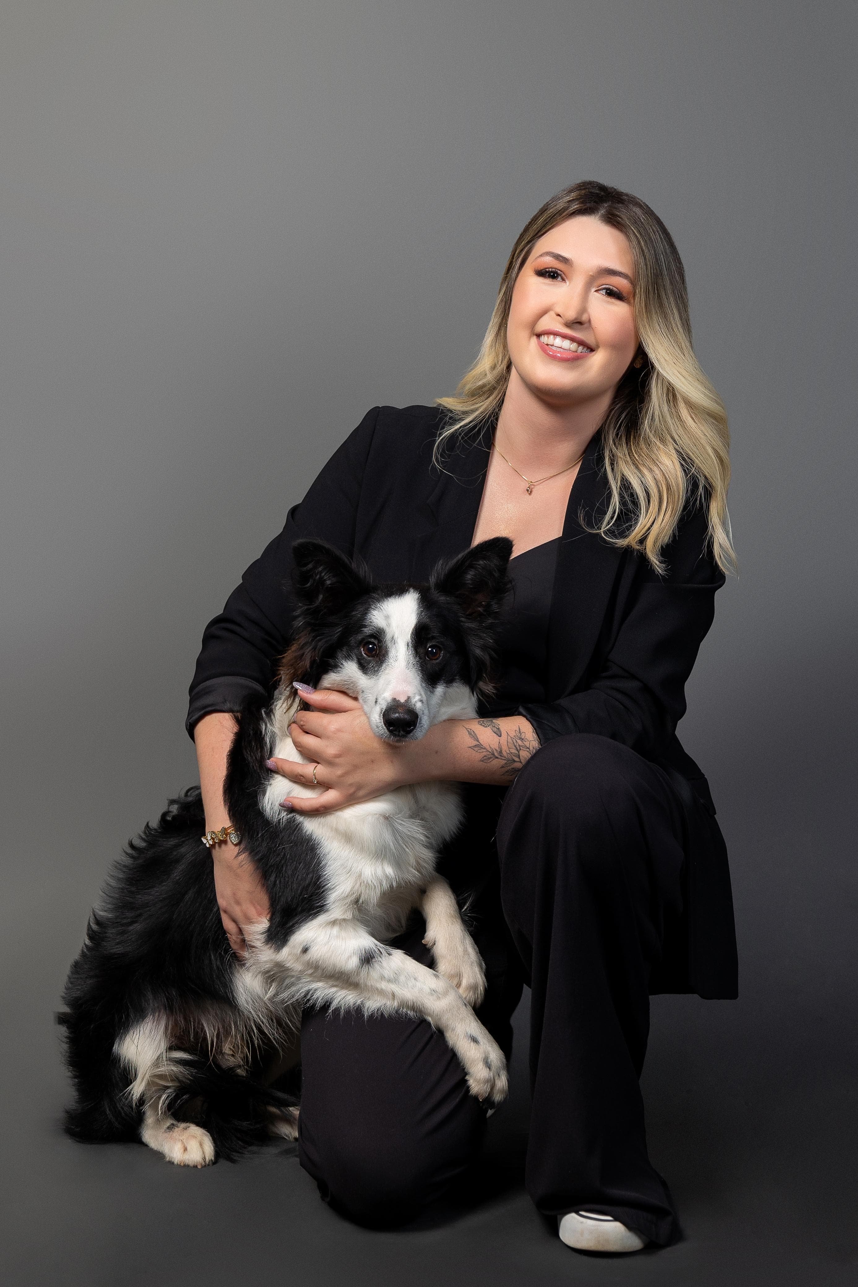 Dra. Luiza Scholz agachada ao lado de um cachorro de porte médio