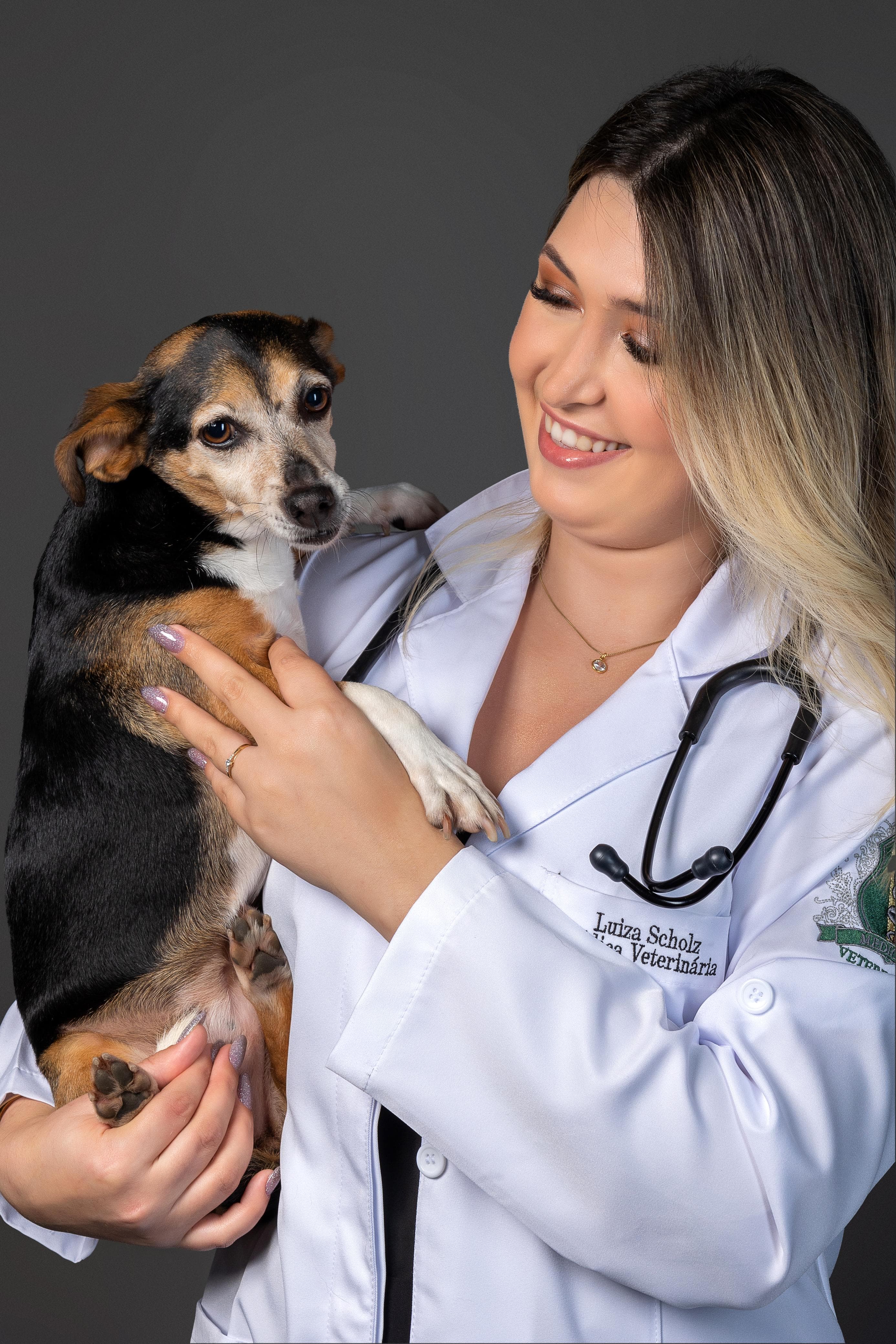 Dra. Luiza Scholz de jaleco segurando um cachorro pequeno no colo